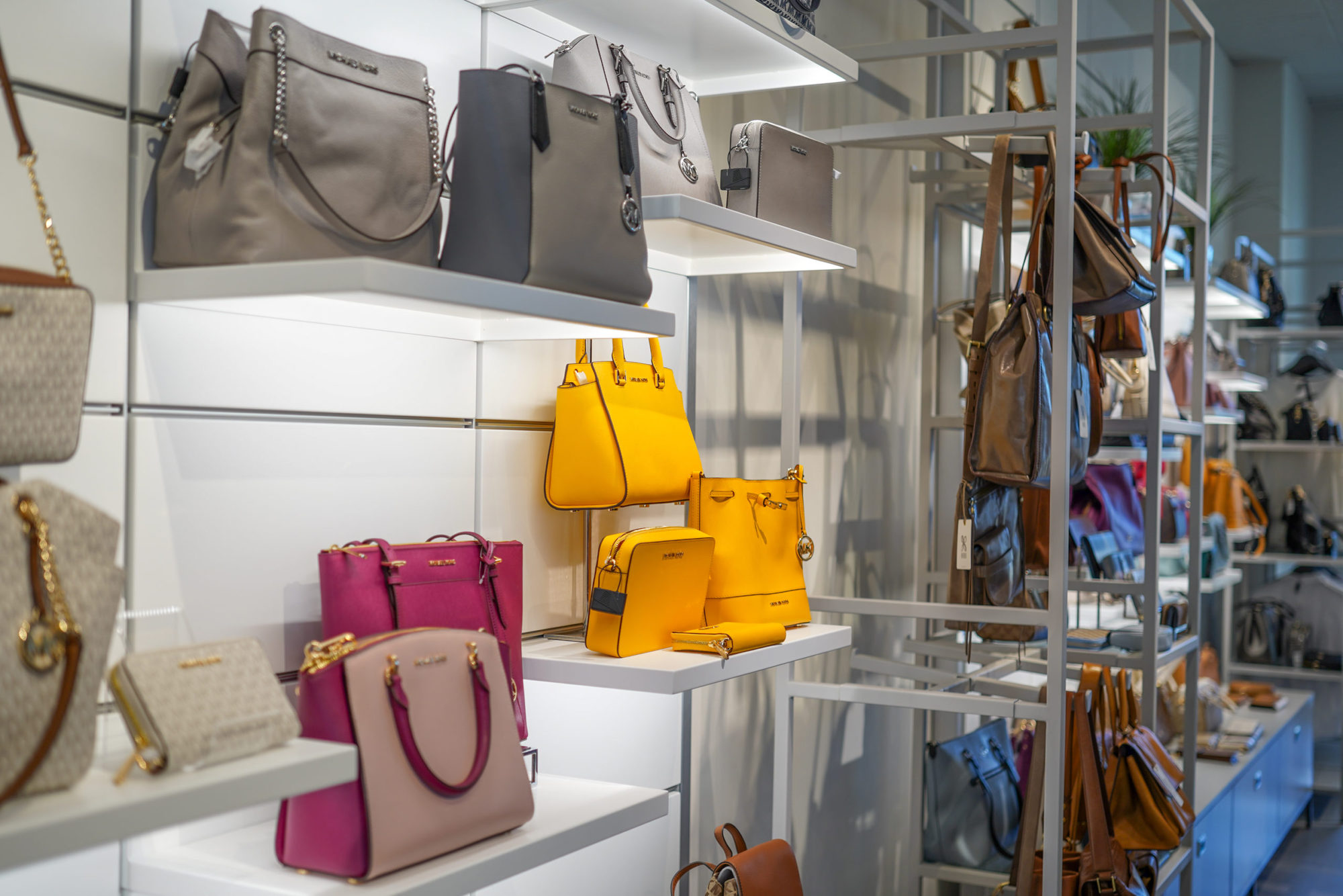 display of yellow, pink and neutral designer purses