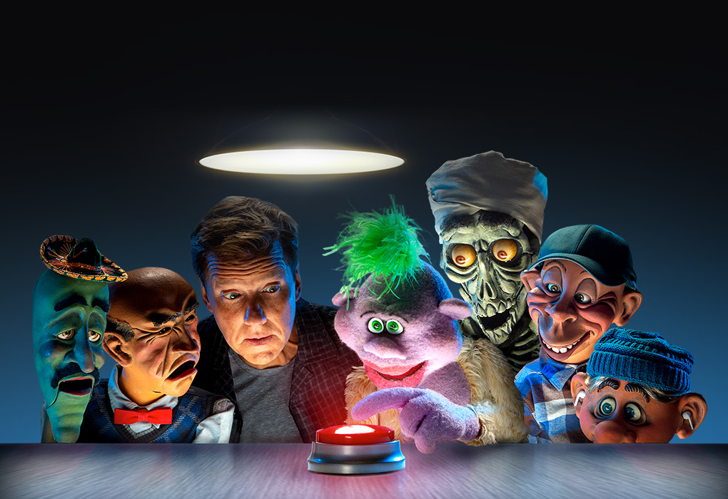 Jeff Dunham and a group of his puppets looking focused on one puppet pushing a red button